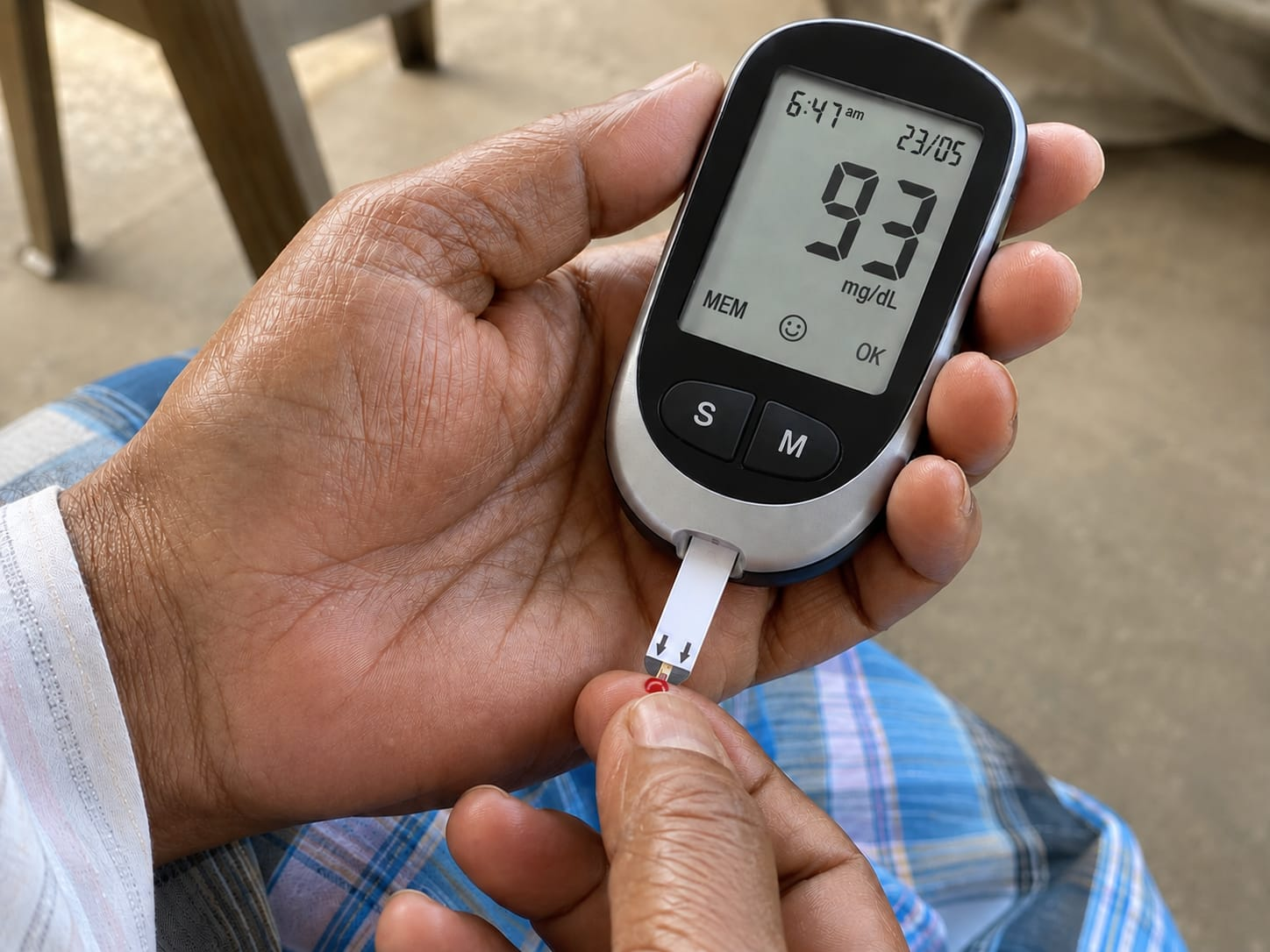 Hand holding a glucometer displaying 93 mg/dL